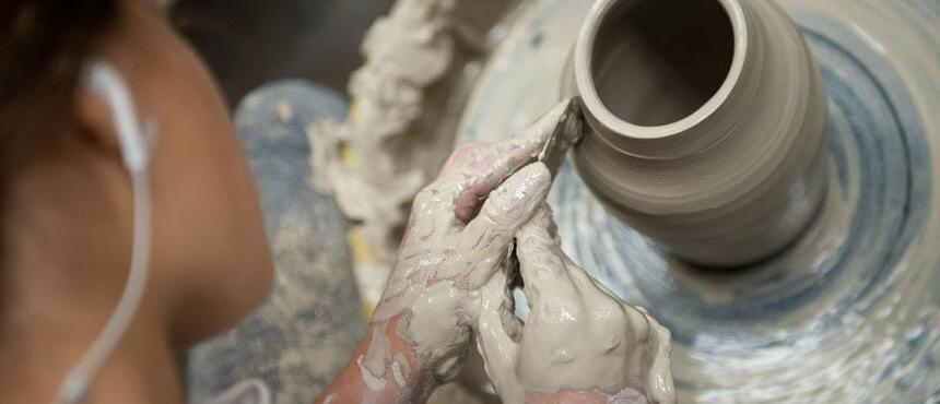 Student throwing pottery on a wheel